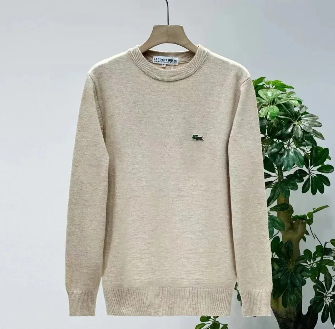 Beige crewneck sweater hanging on a hanger